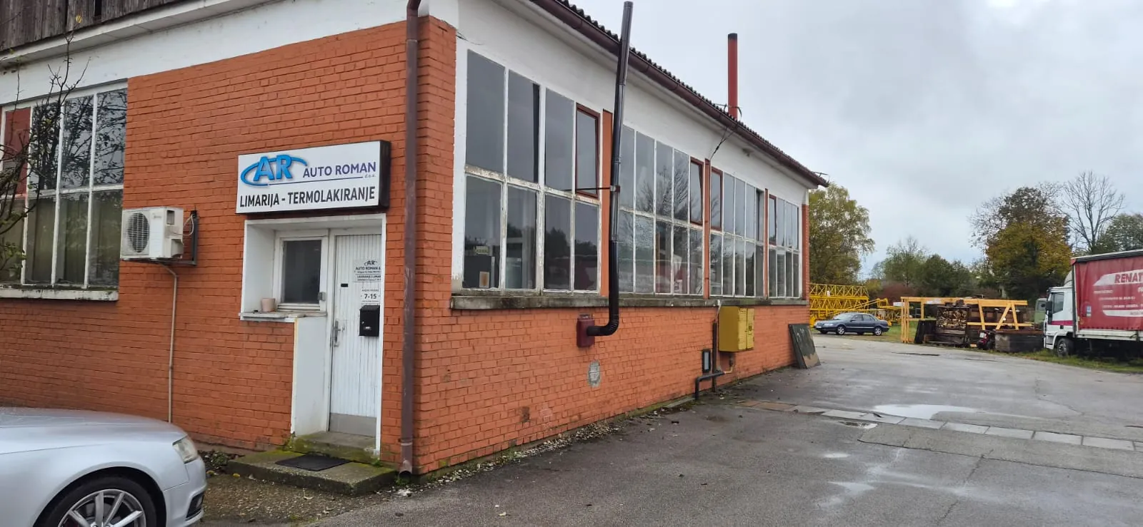 Ulazna vrata ureda ispod natpisa Auto Roman na zgradi od cigle